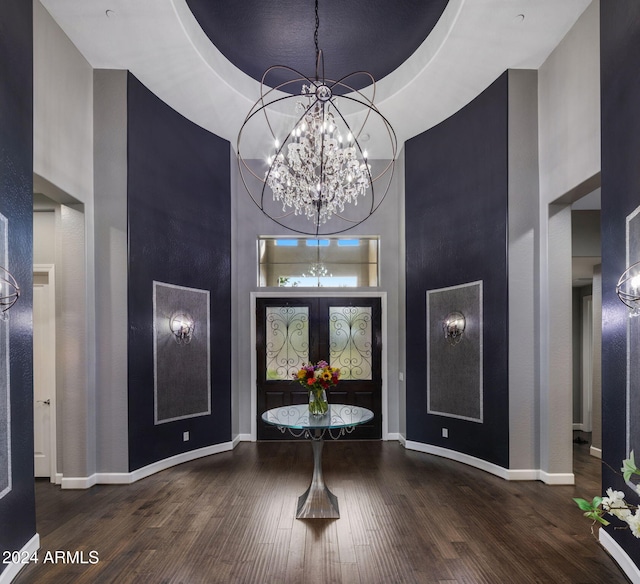 entryway with french doors, a towering ceiling, a notable chandelier, and hardwood / wood-style flooring