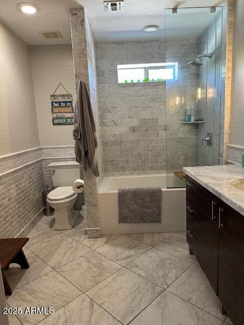 18132 E Vencino St, Gilbert, AZ 85298 - bathroom with toilet, shower / washtub combination, vanity, tile walls, and marble look tiles