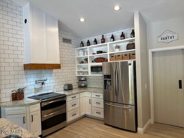 18132 E Vencino St, Gilbert, AZ 85298 - kitchen with appliances with stainless steel finishes, open shelves, white cabinetry, light wood-style flooring, and backsplash