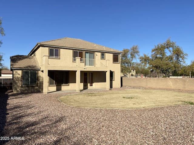 back of property featuring stucco siding, a balcony, and fence