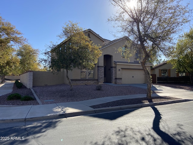 view of front of property featuring stone siding, stucco siding, concrete driveway, and fence