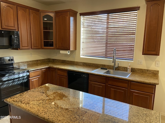 kitchen with a sink, glass insert cabinets, black appliances, and brown cabinetry