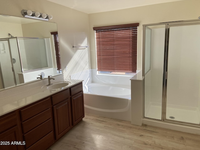 bathroom with vanity, a bath, wood finished floors, and a stall shower