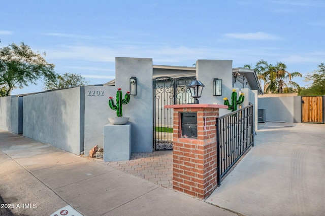 view of front facade featuring a fenced front yard, a gate, and stucco siding