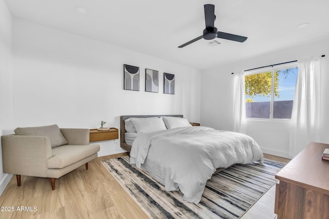 bedroom featuring light wood-style floors, baseboards, visible vents, and ceiling fan