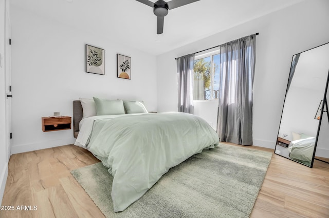 bedroom featuring a ceiling fan, baseboards, and light wood finished floors