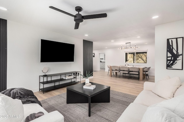 living area featuring ceiling fan with notable chandelier, light wood-type flooring, baseboards, and recessed lighting