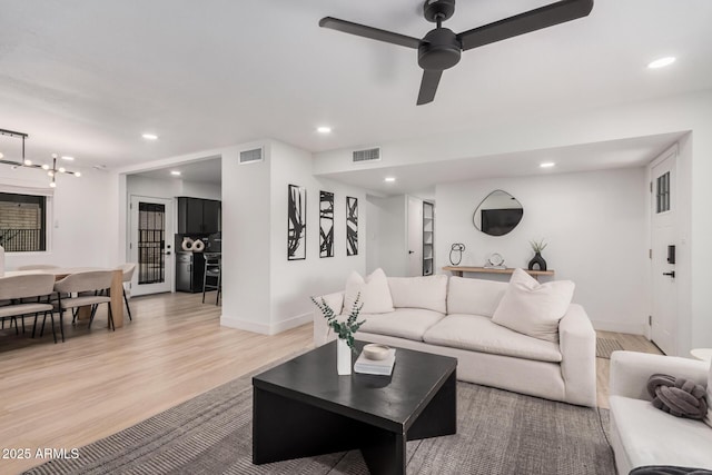 living room with baseboards, light wood-type flooring, visible vents, and recessed lighting