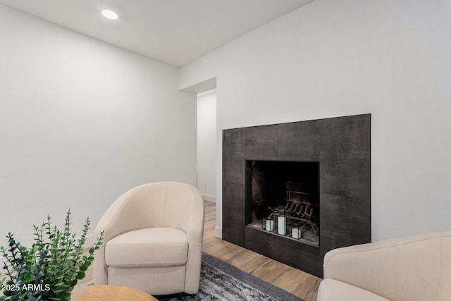 living area featuring a tiled fireplace, wood finished floors, and recessed lighting