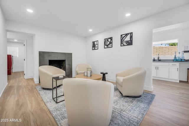 living area with indoor wet bar, light wood finished floors, recessed lighting, a tile fireplace, and baseboards