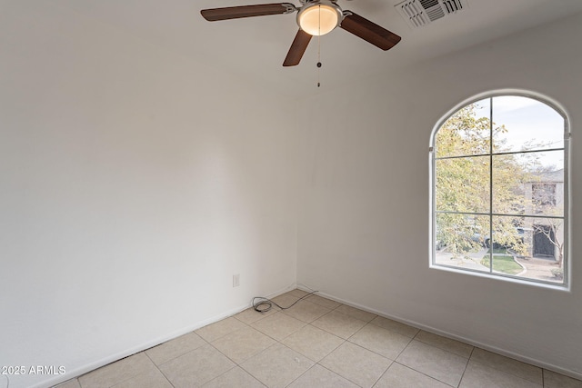 tiled spare room featuring a wealth of natural light and ceiling fan