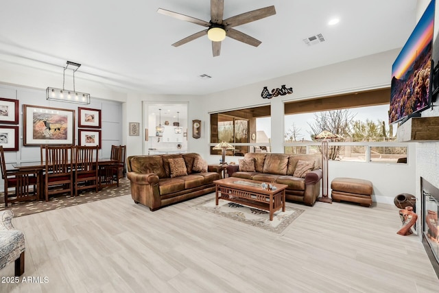 living room with ceiling fan, a wealth of natural light, and light hardwood / wood-style floors