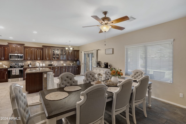 dining area with ceiling fan with notable chandelier and sink