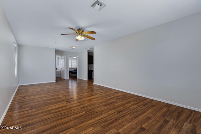 empty room featuring a wealth of natural light, ceiling fan, and dark hardwood / wood-style floors