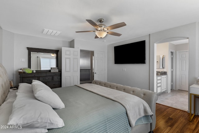 bedroom with wood-type flooring, ensuite bath, and ceiling fan