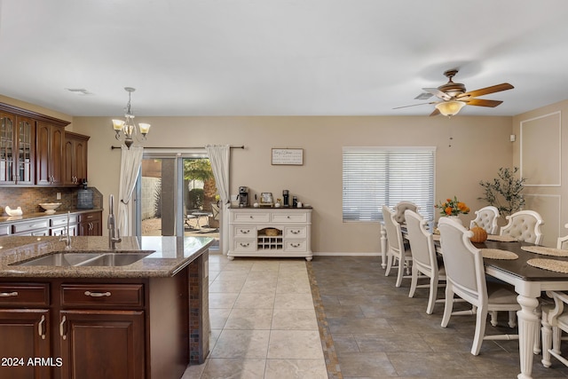 7715 S 69th Ln, Laveen, AZ 85339 - kitchen with tasteful backsplash, ceiling fan with notable chandelier, dark stone countertops, a sink, and glass insert cabinets