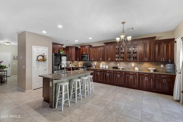 kitchen featuring appliances with stainless steel finishes, a center island with sink, a breakfast bar, dark brown cabinetry, and sink