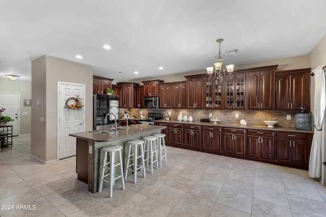 7715 S 69th Ln, Laveen, AZ 85339 - kitchen featuring a breakfast bar area, an inviting chandelier, backsplash, a sink, and appliances with stainless steel finishes
