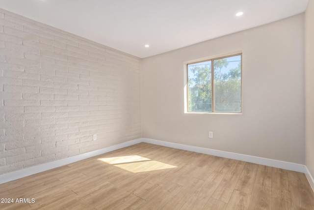 empty room featuring brick wall and light wood-type flooring