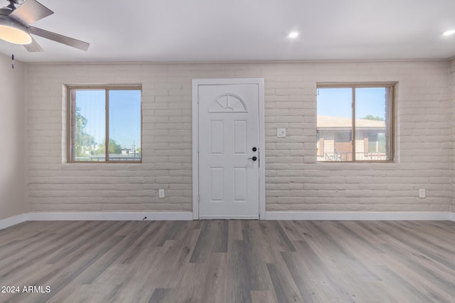 entrance foyer featuring plenty of natural light, wood-type flooring, and brick wall