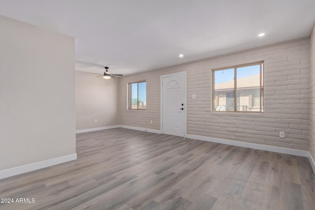 interior space featuring ceiling fan, brick wall, and light hardwood / wood-style floors