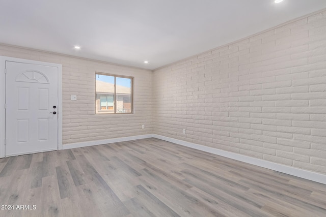 foyer entrance with light hardwood / wood-style flooring and brick wall