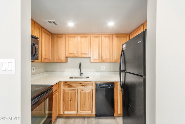 kitchen with light brown cabinets, sink, light hardwood / wood-style flooring, and black appliances