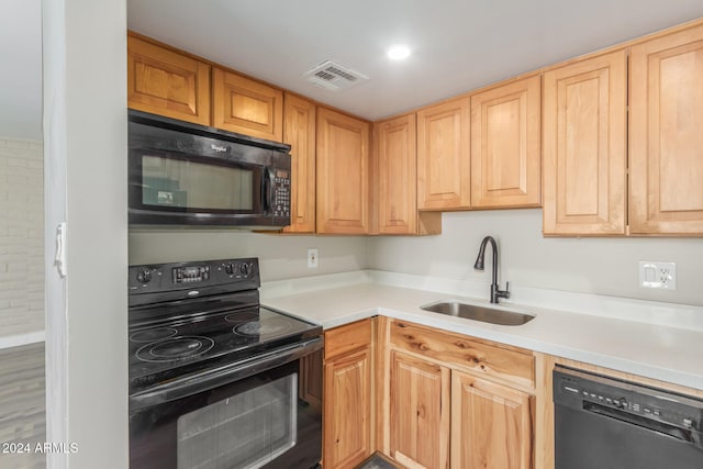 kitchen with sink, black appliances, light brown cabinets, and hardwood / wood-style flooring