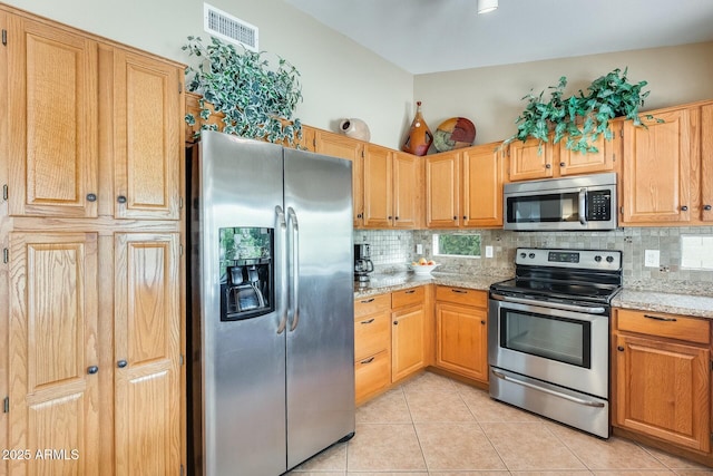 kitchen with light stone countertops, visible vents, stainless steel appliances, and backsplash