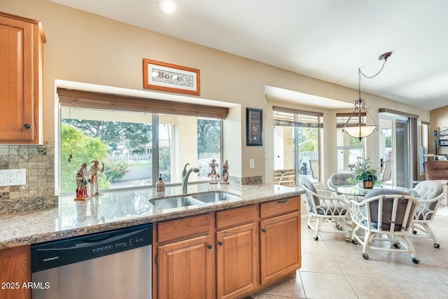 kitchen with sink, light stone counters, tasteful backsplash, decorative light fixtures, and stainless steel dishwasher