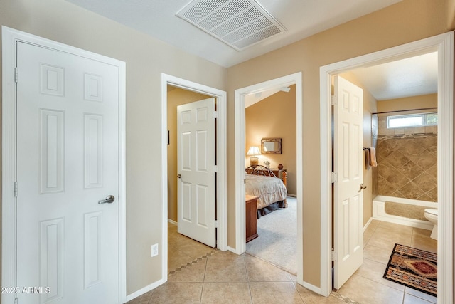 hall featuring light tile patterned floors, baseboards, and visible vents