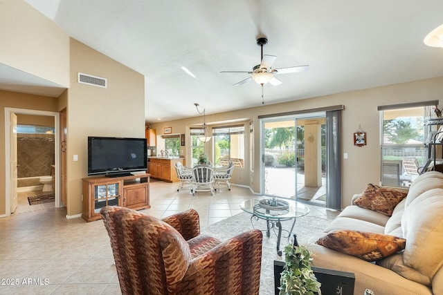 living area featuring lofted ceiling, light tile patterned flooring, visible vents, baseboards, and a ceiling fan