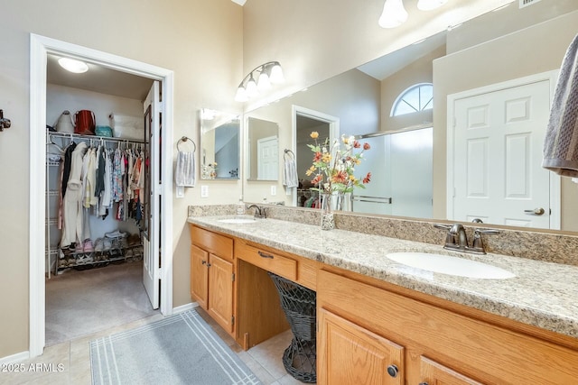 bathroom with a stall shower, a sink, a spacious closet, and double vanity