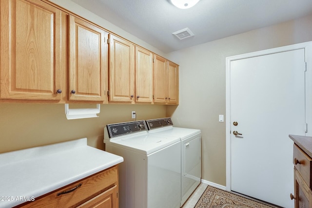 clothes washing area featuring cabinets and washing machine and clothes dryer