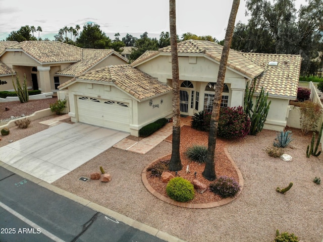 view of front of home featuring a garage, driveway, a tile roof, and stucco siding