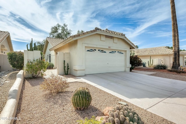 mediterranean / spanish home with a garage, a tile roof, concrete driveway, a gate, and stucco siding