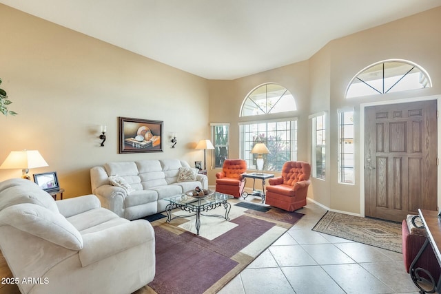 living area featuring a high ceiling, light tile patterned flooring, and baseboards