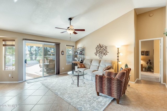 living room with light tile patterned floors, ceiling fan, baseboards, and high vaulted ceiling