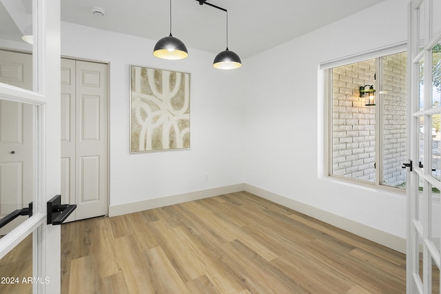 empty room featuring plenty of natural light, wood-type flooring, and french doors