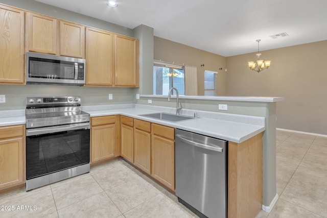 kitchen with appliances with stainless steel finishes, kitchen peninsula, light brown cabinets, sink, and an inviting chandelier