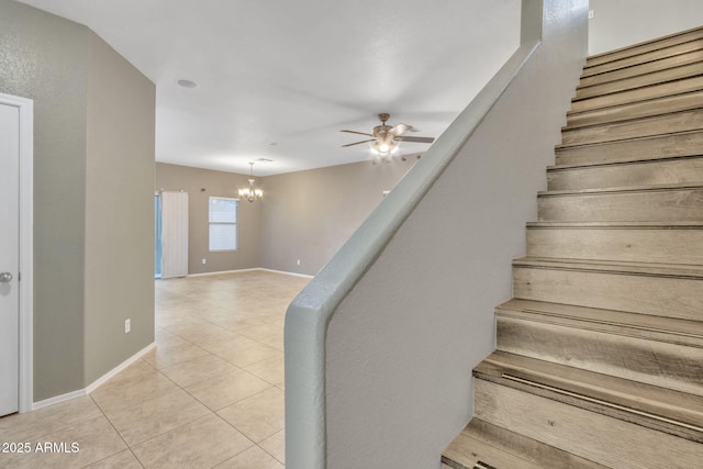 staircase featuring ceiling fan with notable chandelier and tile patterned flooring