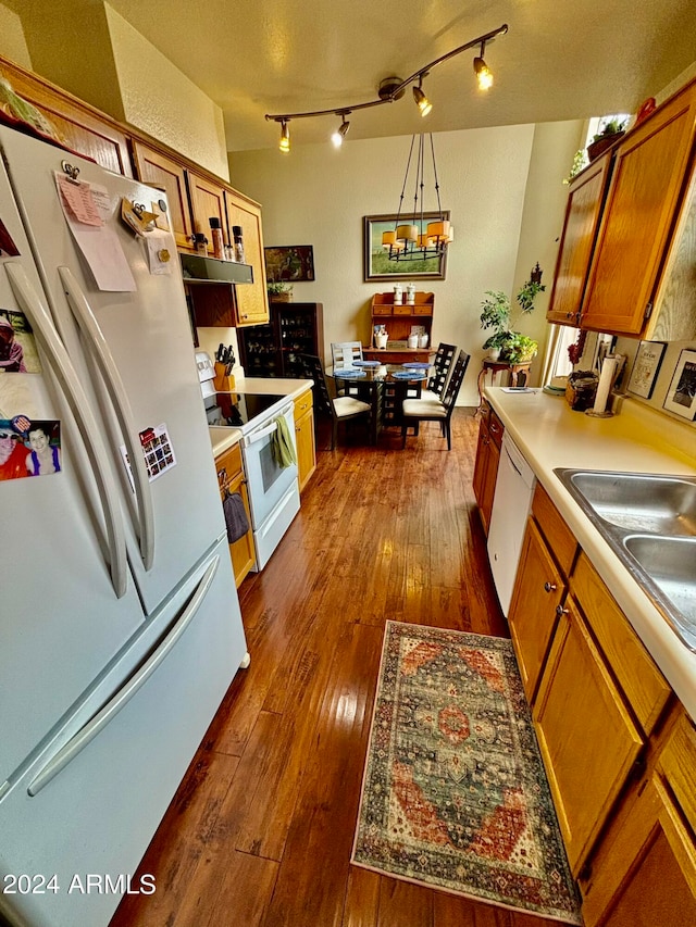 kitchen featuring pendant lighting, dark hardwood / wood-style flooring, white appliances, and sink