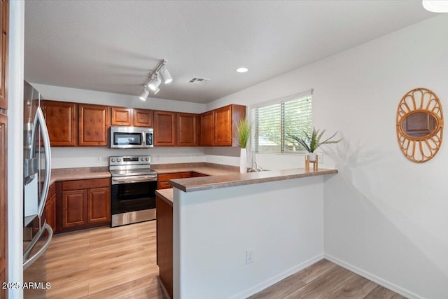 180 S 18th St, Coolidge, AZ 85128 - kitchen with appliances with stainless steel finishes, light wood finished floors, brown cabinetry, a peninsula, and recessed lighting