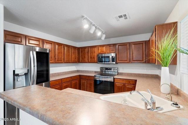 180 S 18th St, Coolidge, AZ 85128 - kitchen featuring stainless steel appliances, a sink, brown cabinetry, and light countertops