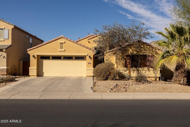 view of front facade featuring a garage, concrete driveway, a tile roof, and stucco siding