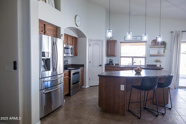 kitchen with plenty of natural light, appliances with stainless steel finishes, dark countertops, and a kitchen bar