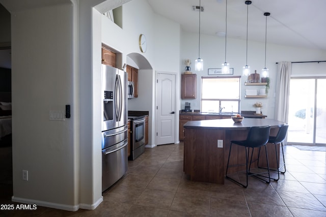 kitchen featuring a breakfast bar area, stainless steel appliances, visible vents, a center island, and decorative light fixtures