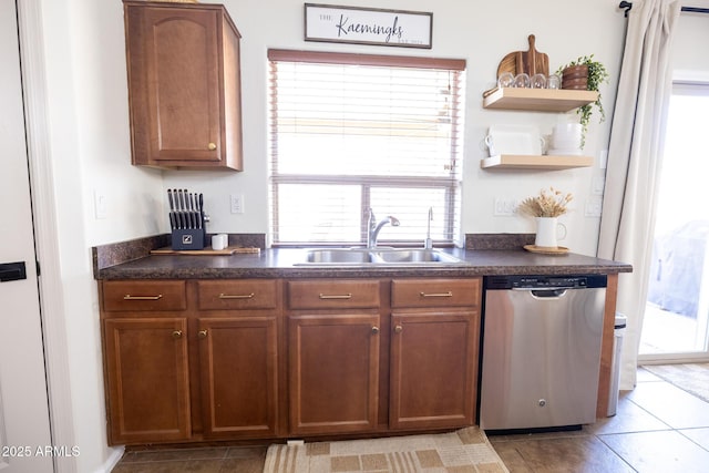 kitchen featuring brown cabinetry, dark countertops, stainless steel dishwasher, open shelves, and a sink