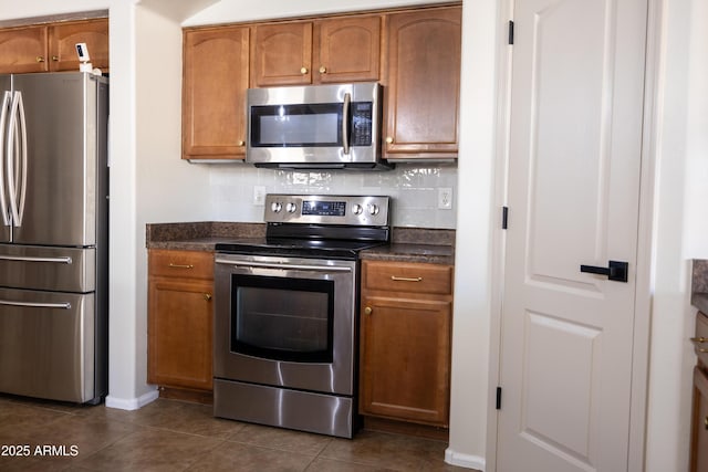 kitchen featuring appliances with stainless steel finishes, dark countertops, brown cabinetry, and decorative backsplash