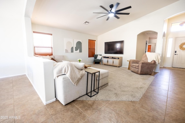 tiled living area with arched walkways, visible vents, vaulted ceiling, and baseboards